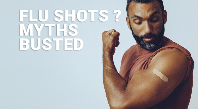 Man flexing his arm with a band-aid after a flu shot on a blue background.