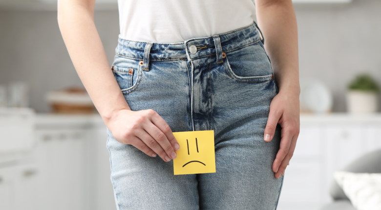 A woman holding a sad face sign over her stomach, symbolizing UTI discomfort and seeking treatment.